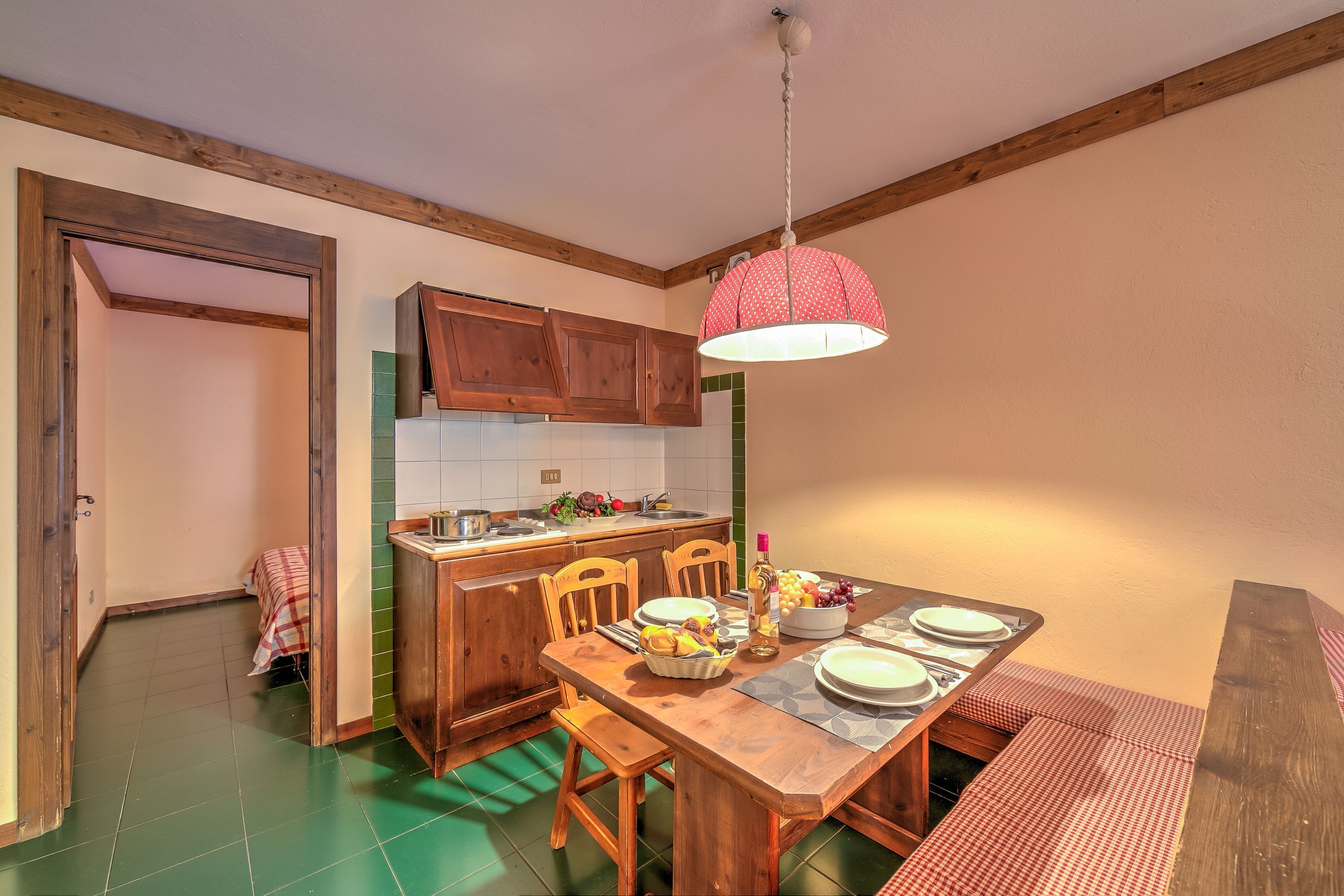 A kitchen with wooden cabinets, a dining table set for four, and a hanging light fixture.