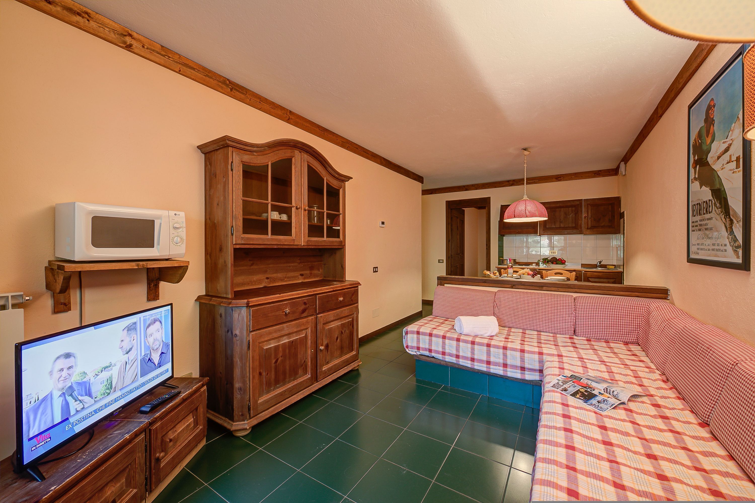 Una sala de estar con televisor, aparador de madera y sofá a cuadros.