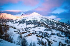 Ein schneebedeckter Berg mit einem Skiort, einschließlich Gebäude und Skipisten.