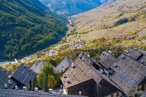 A mountainous village with traditional wooden houses, a river, and a valley. - Grange Hike Ski - 7C Sestriere (Sauze di Cesana)