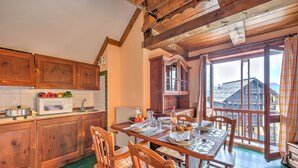 Een keuken met houten kastjes, een magnetron en een eethoek met een tafel gedekt voor twee personen.