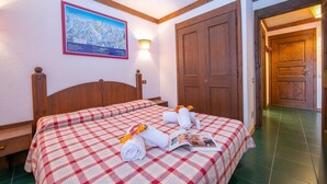 A hotel room with a checkered bedspread, a wooden headboard, a map on the wall, and a wooden door.