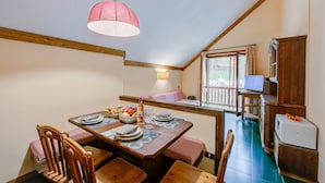 A dining area with a wooden table set for four, a pink pendant light, and a view of the outside through a window. - Grange Hike Ski - 45D Sestriere (Sauze di Cesana)
