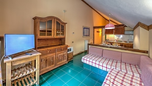 A cozy living room with a television, wooden cabinet, and a checkered sofa. - Grange Hike Ski - 45D Sestriere (Sauze di Cesana)