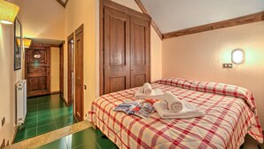A bedroom with a plaid bedspread, a bedside table with a magazine, and a wall-mounted light. - Grange Hike Ski - 45D Sestriere (Sauze di Cesana)