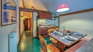 A kitchen with wooden cabinets, a dining table set for four, and a hanging light fixture. - Grange Hike Ski - 45D Sestriere (Sauze di Cesana)