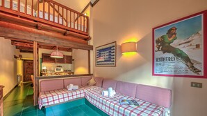A cozy room with a checkered sofa, a wooden staircase, and a poster on the wall.