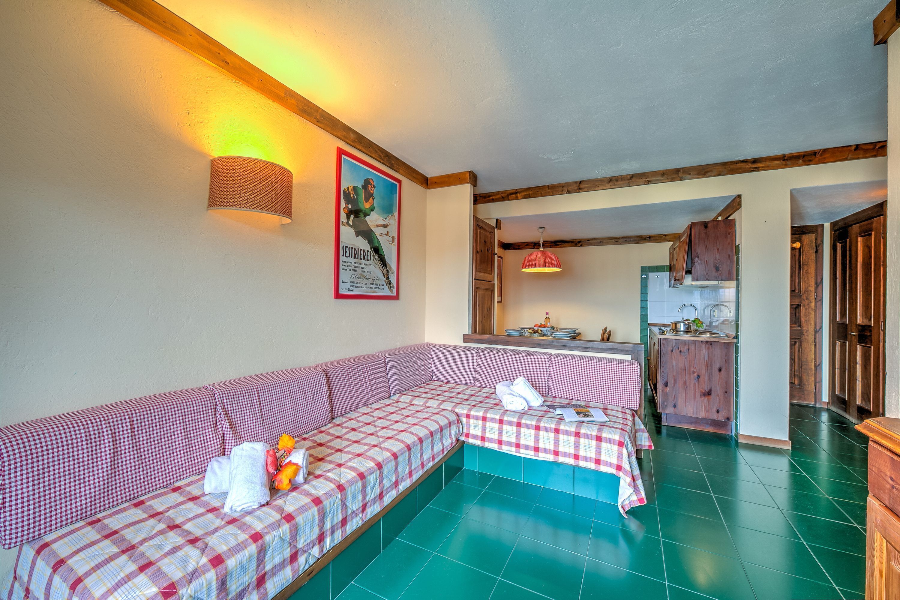 Una habitación acogedora con un sofá a cuadros, una zona de cocina y una viga de techo de madera.
