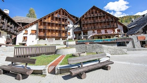 A traditional wooden building with balconies, a stone pathway, and a wooden bench in a sunny outdoor setting. - Grange Hike Ski - 26D Sestriere (Sauze di Cesana)