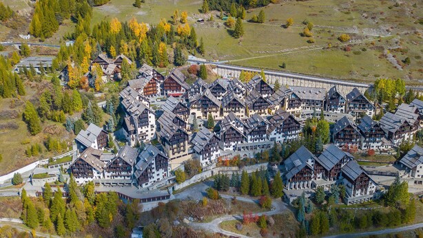 An aerial view of a resort with chalet-style buildings, surrounded by trees and a ski lift. - Grange Hike Ski - 26D Sestriere (Sauze di Cesana)