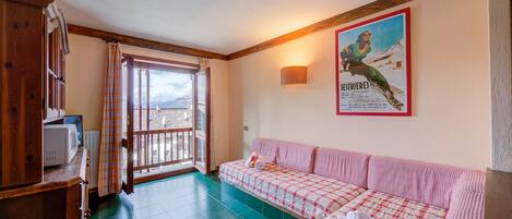 Una habitación acogedora con un sofá a cuadros, un aparador de madera y un cartel en la pared.