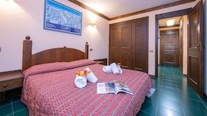 Una camera d'albergo con un letto grande, una testiera in legno, una mappa appesa al muro e un pavimento piastrellato verde.