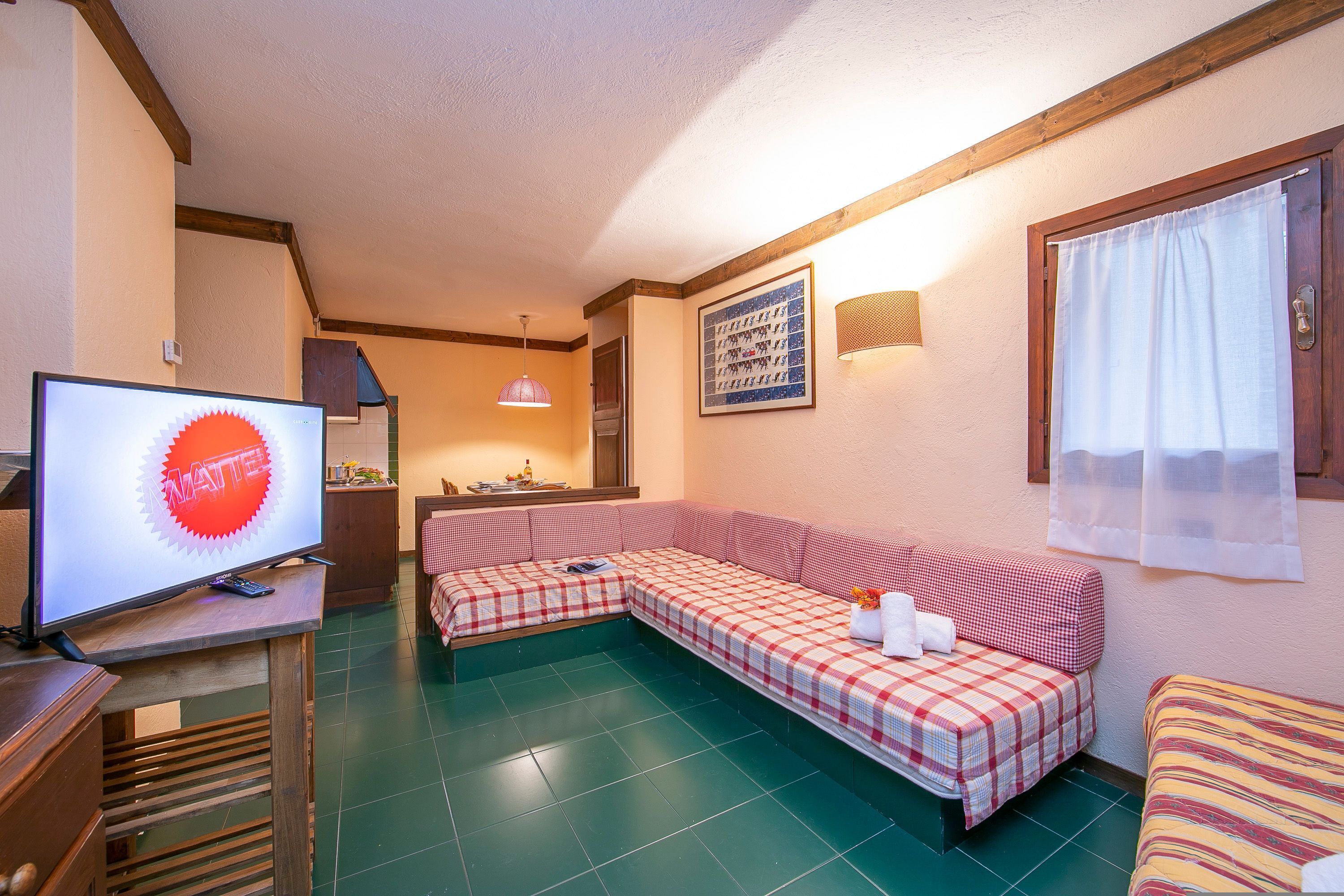 A cozy room with a checkered sofa, a television, and a dining area.