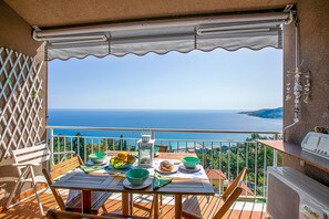 Un balcón con una mesa lista para una comida, con vista a un paisaje marino.