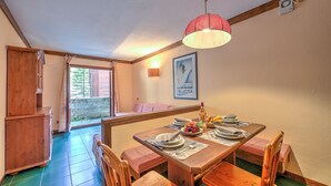 A dining area with a wooden table set for four, a hanging light fixture, and a framed picture on the wall. - Grange Hike Ski - 23C Sestriere (Sauze di Cesana)