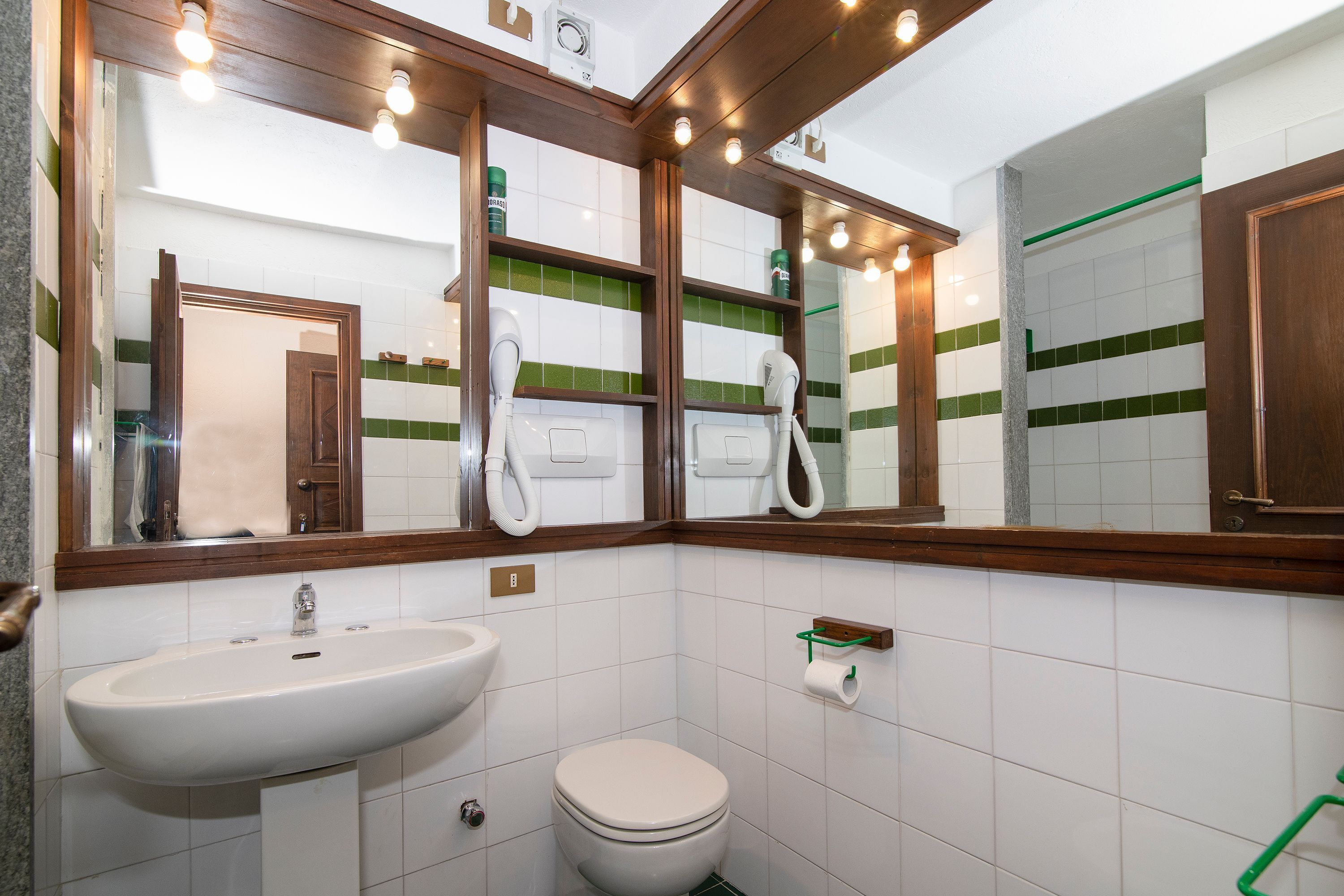 Un baño con lavamanos, inodoro y espejos.