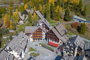 Un edificio de estilo chalé tradicional con un patio central, rodeado de árboles y una pequeña carretera.