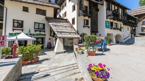 A traditional European town square with stone buildings, a bar, and potted plants. - Grange Hike Ski - 30D Sestriere (Sauze di Cesana)
