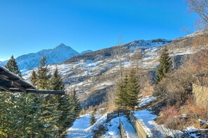 Un paysage montagneux aux pentes enneigées, avec une clôture en bois.