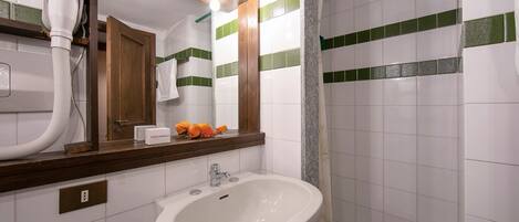 Un bagno con un lavandino bianco, uno specchio e un asciugacapelli.