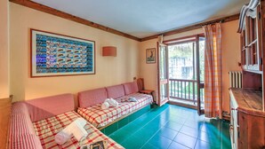 A room with a checkered sofa, a framed photo collage, and a view through an open door. - Grange Hike Ski - 32D Sestriere (Sauze di Cesana)