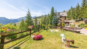 Une vue sur la montagne, avec une clôture en bois, des pots de fleurs et une balançoire en bois.