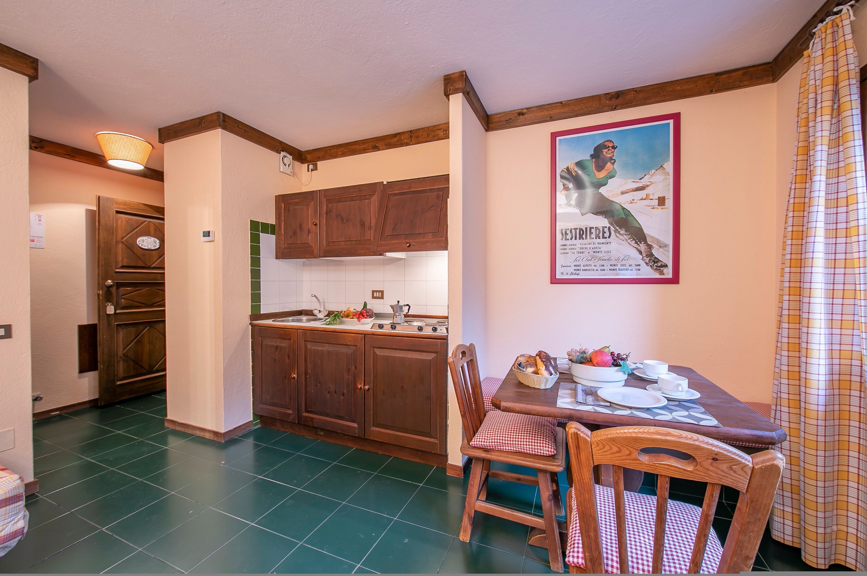 Une cuisine avec des meubles de rangement en bois, une table à manger avec des chaises et une affiche accrochée au mur.