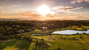 A golf course with bunkers, a pond, and a sunset in the background. - Albarella Maisonette S3M 2 (Rosolina)