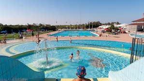 A swimming pool area with multiple pools, including a central pool and a smaller pool with a water slide. - Albarella Maisonette S3M 2 (Rosolina)