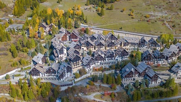 An aerial view of a resort with chalet-style buildings, surrounded by trees and a ski lift. - Grange Hike Ski - 41D Sestriere (Sauze di Cesana)