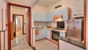A modern kitchen with light blue cabinets, a stainless steel refrigerator, and a built-in oven.