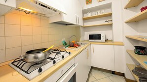 A kitchen with a gas stove, microwave, and white cabinets. - Il Sogno Di Silvana in Sanremo (Sanremo)