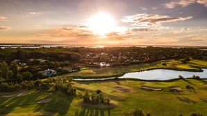 Ett flygbildsbild av en golfbana med en sjö, omgiven av träd och bostadsområden.
