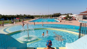A swimming pool with multiple lanes, a diving platform, and a spectator area with umbrellas. - Albarella S3 1 in Isola Albarella (Rosolina)
