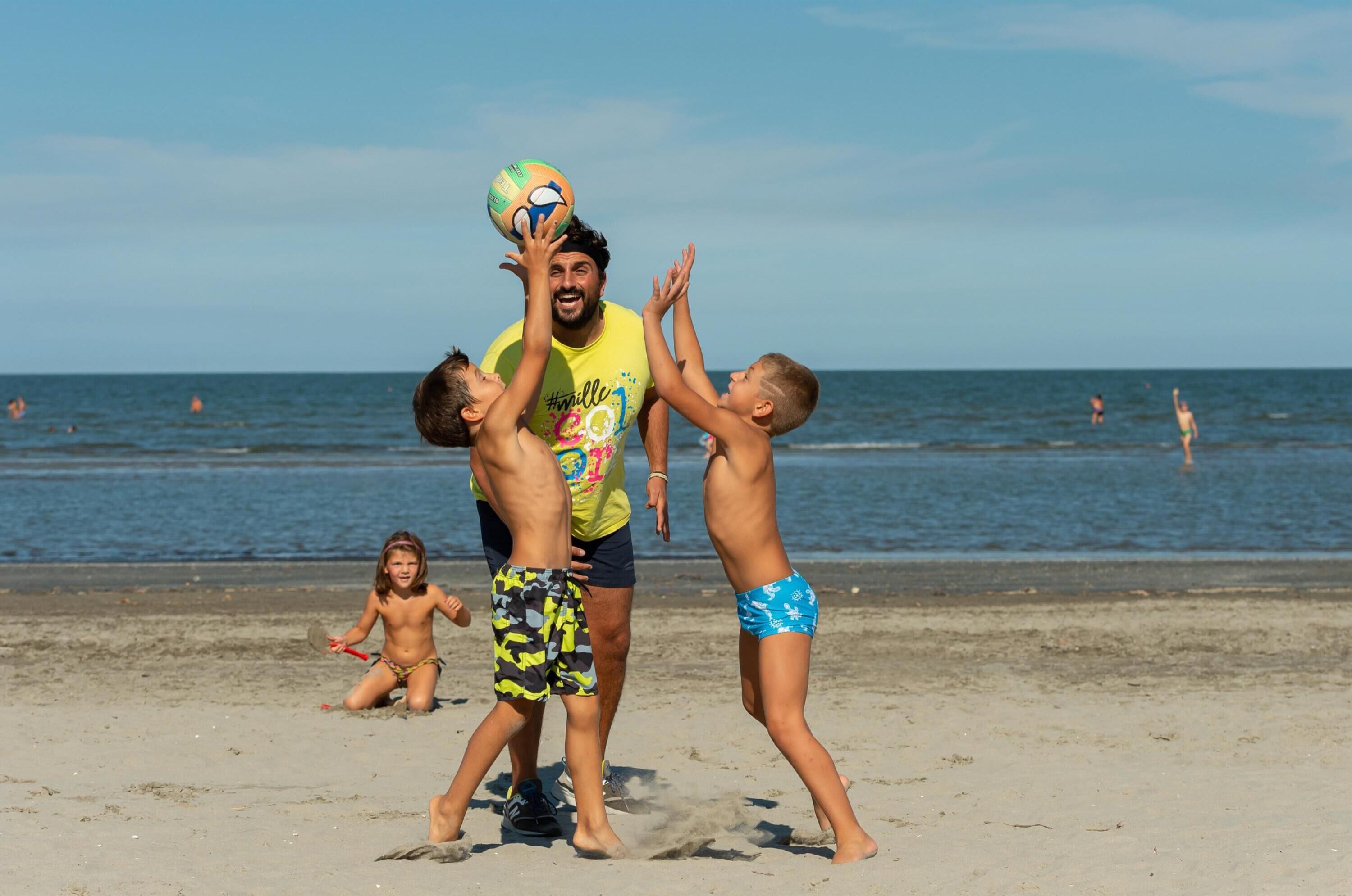 A beach scene with people playing with a ball.
