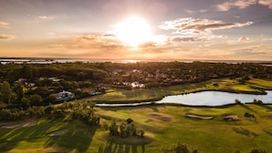 An aerial view of a golf course with a lake, surrounded by trees and residential areas. - Albarella S3 2 in Isola Albarella (Rosolina)