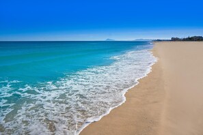 Une plage aux eaux turquoise et limpides, bordée d’un rivage sablonneux.