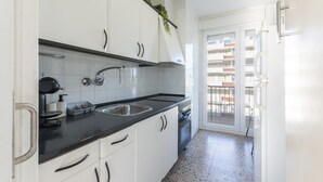 Une cuisine avec des armoires blanches, un plan de travail noir, un évier et une cuisinière.