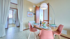 A dining area with a round table, pink chairs, a floor lamp, and a framed picture on the wall. - La Perla Bianca Lake View (Massino Visconti)