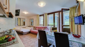 A modern kitchen with a dining area, a sofa bed, and a TV.