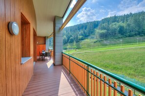 A wooden deck with a view of a green field and forest. - La Marmotta Campo Smith on the Ski Slopes (Bardonecchia)