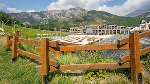 A hotel with a view of mountains, a wooden fence, and a grassy area.