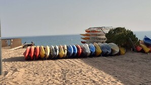 Una playa con una fila de kayaks y una torre de salvavidas al fondo.