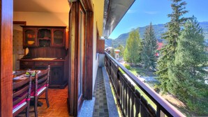 A balcony with a wooden railing, a dining table with chairs, and a view of a mountainous landscape. - Il Nido di Elda few Steps From Skiing (Bardonecchia)