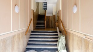 A staircase with wooden handrails, beige walls, and a tiled floor. - Central Flat in Camogli (Camogli)