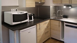 A compact kitchen with a microwave, coffee maker, and dishwasher. - Renovated large studio for 4, center station, ski-in/ski-out (Les Orres)