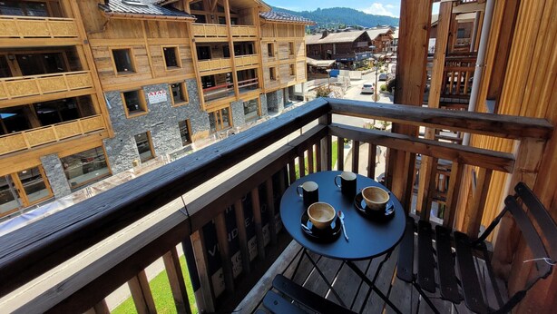 Un edificio de madera con varios balcones y una mesa con tazas en un balcón.