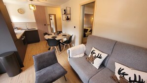 Una sala de estar moderna con un sofá gris, dos sillas negras, una mesa de centro de madera y un sillón a rayas.