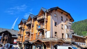 Un edificio de madera de varios pisos con balcones, un letrero que dice 'Montagne Pain' y un cartel de 'Location'.
