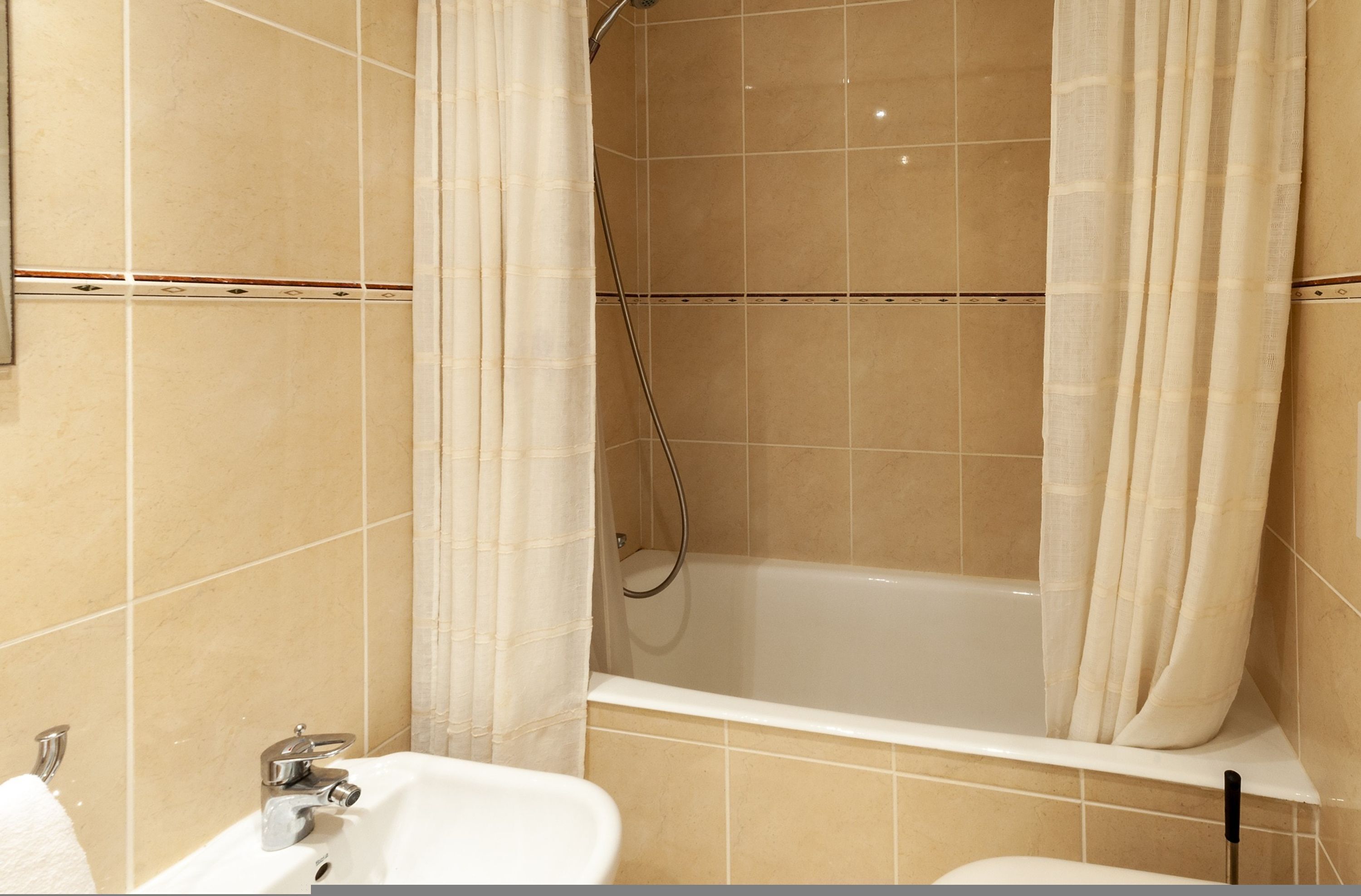 Een badkamer met een bad, een douche en een wastafel.